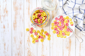bowl of tasty corn rings and strawberry rings with milk on a light kitchen table. Copy space for text. Top view.