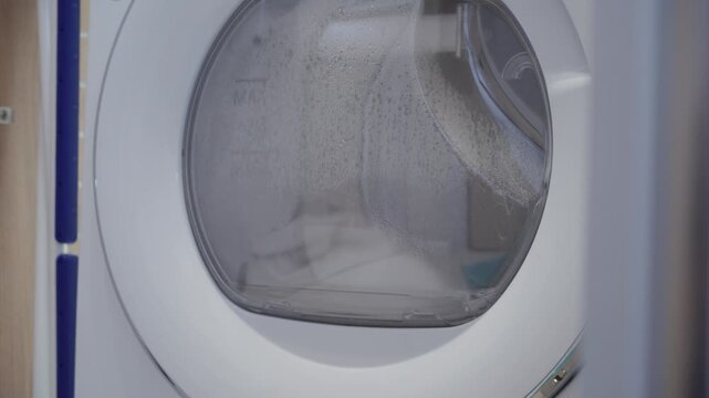 Laundry In Motion: Dryer Tumbles Wet Clothes with a Steady Whirring.