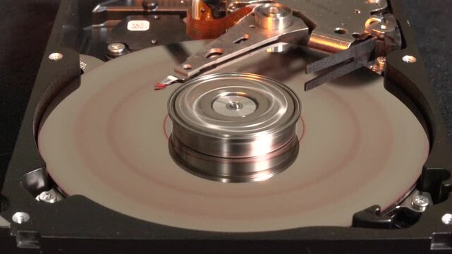 Open hard drive spinning with yellow flashing light effects, stopped spinning, and HACKED appears on the surface