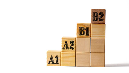 Wooden cubes stacked on ladder with letters A1, A2, B1, B2 on white background, graphic resource, concept of language learning levels of language proficiency © Alena