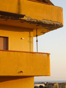 Yellow and Orange Building with Balcony and Scaffolding at Sunset in Scalea, Italy with Sea in Background