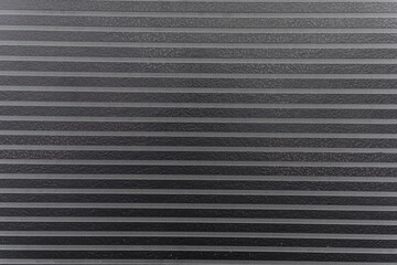 Obraz premium Close-up black textured surface with parallel lines and patterns for modern design backdrop 