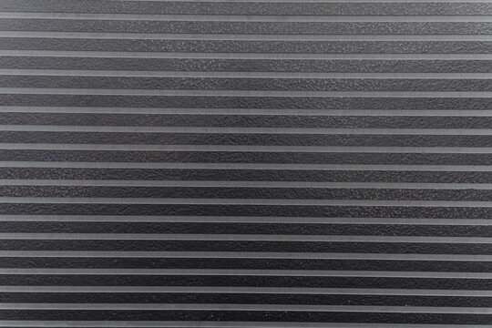 Close-up black textured surface with parallel lines and patterns for modern design backdrop
