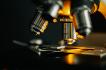 Macro close-up of microscope lens focusing light on a glass slide sample
