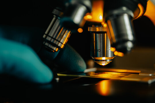 Macro close-up of microscope lens focusing light on a glass slide sample