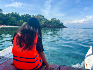 Traveler enjoying stunning ocean view from boat wearing life vest on bright sunny day feeling free