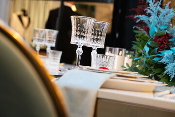 Elegant wedding table setting with crystal glasses, fine china plates, and delicate floral arrangement. Luxury wedding decor with sparkling glassware and refined tableware, creating a wedding decor