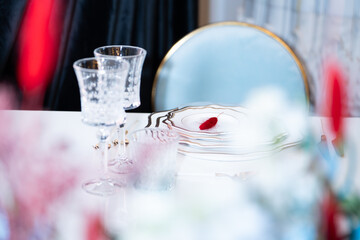 Elegant wedding table setting with crystal glasses, fine china plates, and delicate floral arrangement. Luxury wedding decor with sparkling glassware and refined tableware, creating a wedding decor