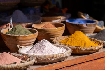 Various vibrant colors, traditional setting on blurred background. Colorful dye pigments in the medina of Marrakech. Natural color pigments powder in bowls on wooden table in Marrakesh, Morocco. 