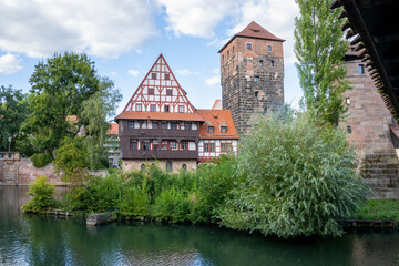 Obraz premium Picturesque view of Henkerhaus Museum, Wasserturm, and the Henkersteg bridges in Nuremberg, Bavaria, spanning the Pegnitz River amid charming medieval architecture.