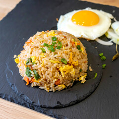 Delicious fried rice and sunny side up egg on black stone plate