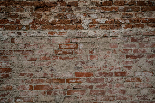 Fototapeta Stara ceglana ściana z odpadającym tynkiem – tekstura cegieł i zaprawy w naturalnych, ciepłych kolorach