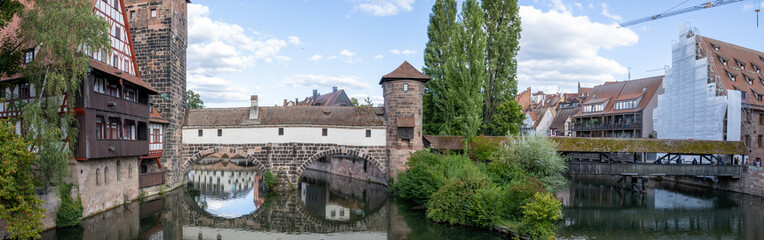 Fototapeta premium Picturesque view of Henkerhaus Museum, Wasserturm, and the Henkersteg bridges in Nuremberg, Bavaria, spanning the Pegnitz River amid charming medieval architecture.