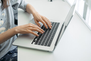 Hands typing on laptop keyboard in modern workspace