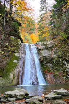 A stunning waterfall surrounded by forest in the mountain heartland during autumn