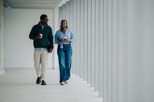 Colleagues walking, talking during office coffee break