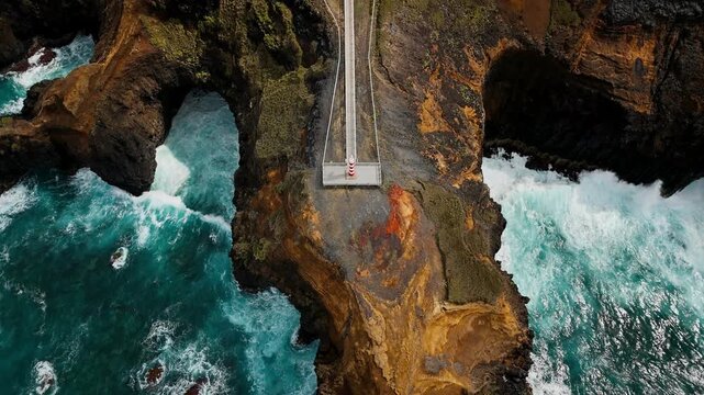 Scenic rugged rocks with small lighthouse Fenais da Ajuda on Azores, Sao Miguel island. Aerial view above, backward flight