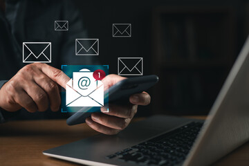 Businessman checking new email notification on smartphone with laptop on desk, concept of digital communication, online messaging, email marketing, and modern business connection.