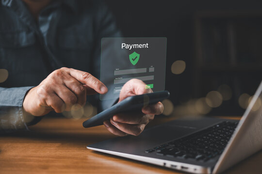 Man making secure online payment using smartphone and laptop with digital interface, concept of mobile banking, fintech, e-commerce transaction, and financial technology security.