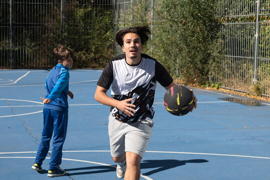 Man dribbling basketball with boy on court