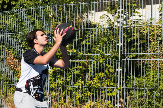 Man focusing on shooting a basketball on an outdoor court