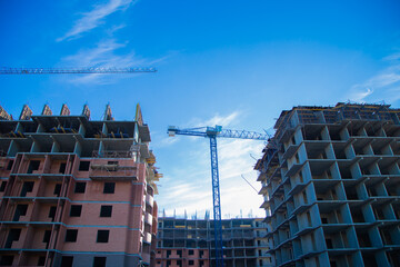 The construction of two large buildings, surrounded by cranes and scaffolding, against a clear blue sky, demonstrates the development of the city and architectural progress. The concept of