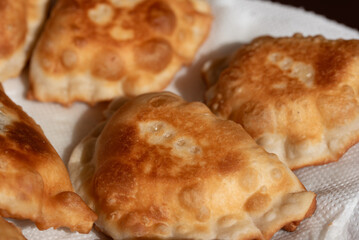 Freshly prepared traditional pastries from Sicily, known as “ravioli dolci,” are laid out on a plate. The pastries are placed on a paper kitchen towel to drain.