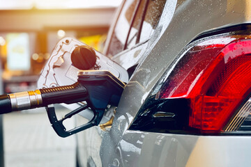 Car refueling on the petrol station. nozzle fuel fill oil into car tank at pump gas station. gasoline era.rain drops on a car.close up. 
