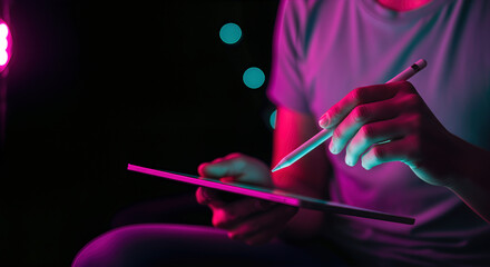 Person using digital tablet with stylus in vibrant neon light. A close-up shot showcasing modern technology and creativity. Digital lifestyle, innovative design, creative process.
