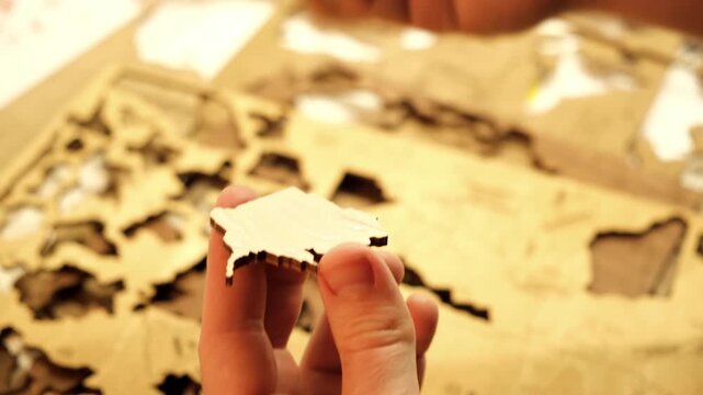 A man smears a wooden part with PVA glue in close-up. The creative process of creating DIY crafts. Gluing a world map from individual pieces of countries. Hobby concept. Carpentry. High quality 4K.