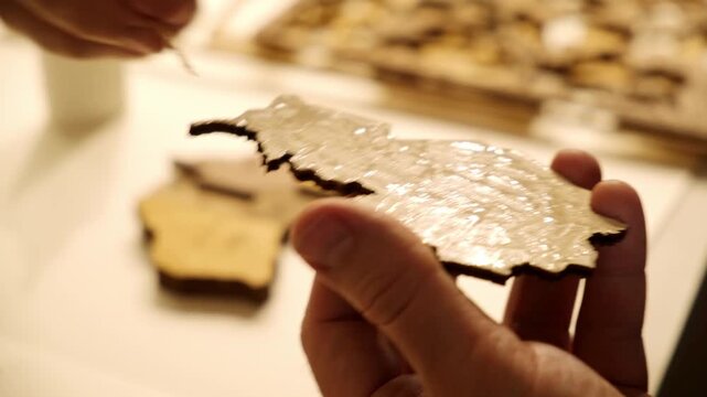 A man smears a wooden part with PVA glue in close-up. The creative process of creating DIY crafts. Gluing a world map from individual pieces of countries. Hobby concept. Carpentry. High quality 4K.