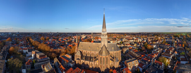 A stunning aerial view of De Gouwekerk in Gouda, with its majestic spire rising above the historic canals and rooftops of the old Dutch city.