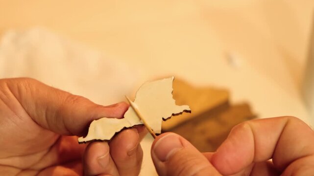A man smears a wooden part with PVA glue in close-up. The creative process of creating DIY crafts. Gluing a world map from individual pieces of countries. Hobby concept. Carpentry. High quality 4K.