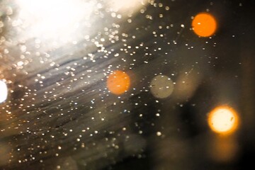 Abstraktes Motiv Frostmuster auf beschlagener Glasscheibe vor orange-gold-braunen runden Licht und dunklem Himmel in der Stadt bei Frost, Kälte und Sturm in der Nacht im Winter