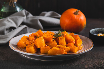 Pieces of baked pumpkin with rosemary on a plate on the table