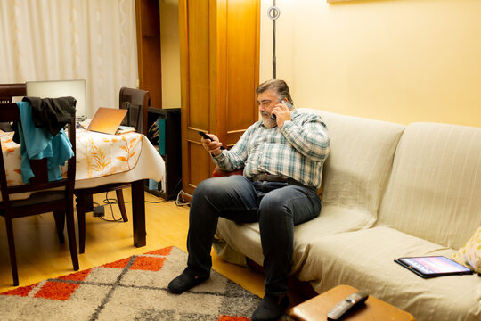 Man multitasking on couch calling with remote control