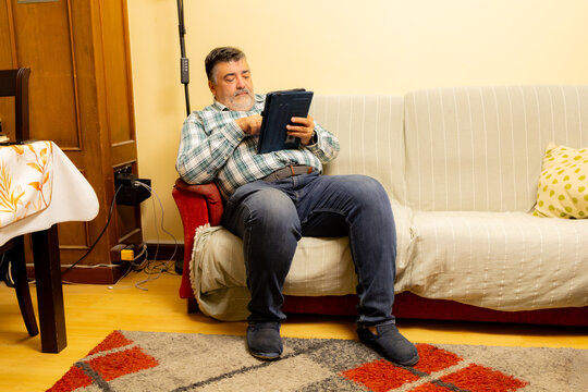 Mature man relaxing on sofa using digital tablet