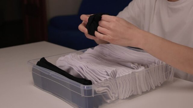 Pairing and arranging socks neatly, Carefully folding and aligning socks on clean surface, Meticulously organizing socks into perfect rows for tidy and efficient routine