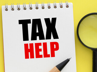 TAX HELP word in the office notebook on a yellow background.