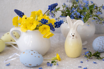 Easter still life with flowers, decorative Easter bunny and eggs on the table