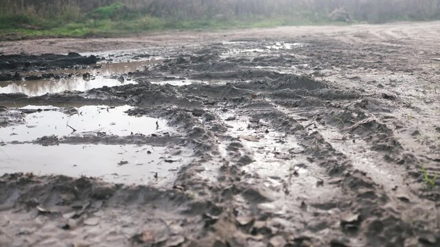 Bad muddy dirt сountry road after the rain puddles and car track. 