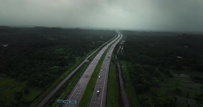 Aerial view of the Mumbai-Nagpur Expressway, also known as Samruddhi Mahamarg, captured during the monsoon season. The modern highway stretches through lush green landscapes, rain-soaked fields.