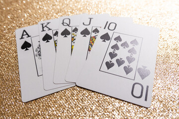 Photograph of a winning hand of a Royal Flush in the poker card game on a gold background