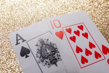 Photograph of a set of cards making a winning hand, Natural Blackjack, on a gold background
