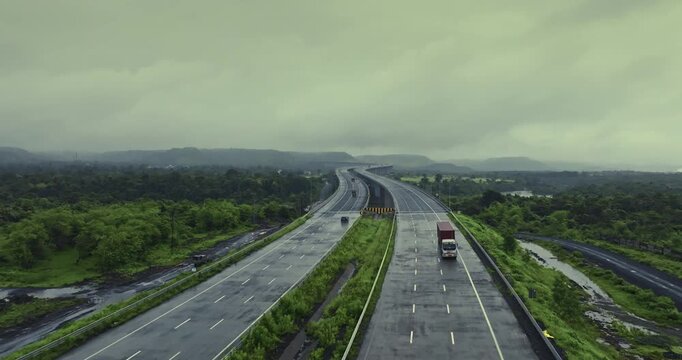 Aerial view of the Mumbai-Nagpur Expressway, also known as Samruddhi Mahamarg, captured during the monsoon season. The modern highway stretches through lush green landscapes, rain-soaked fields.