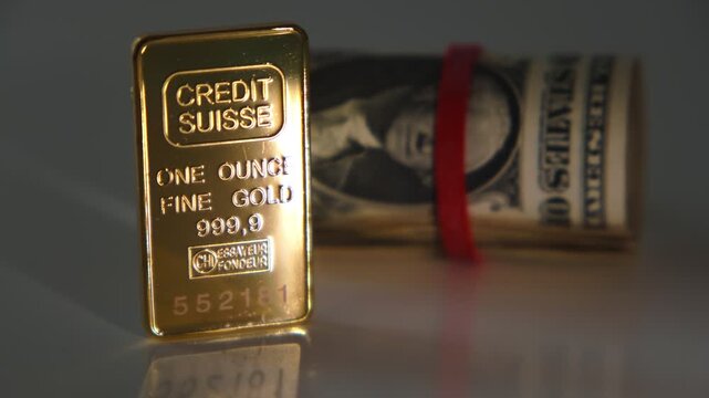 Pure one ounce gold bar from credit suisse bank with a roll of us dollar bills
