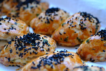 Homemade cheese and parsley pastries. Kohleria fuchsia in the background. Traditional Turkish breakfast pastries. Delicious pastries with black cumin. Ramadan iftar and sahur menu.