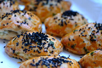 Homemade cheese and parsley pastries. Kohleria fuchsia in the background. Traditional Turkish breakfast pastries. Delicious pastries with black cumin. Ramadan iftar and sahur menu.