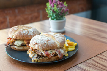 Food photography of a homemade hamburger with bacon and fries placed on a gray plate on a table