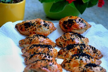 Homemade cheese and parsley pastries. Kohleria fuchsia in the background. Traditional Turkish breakfast pastries. Delicious pastries with black cumin. Ramadan iftar and sahur menu.